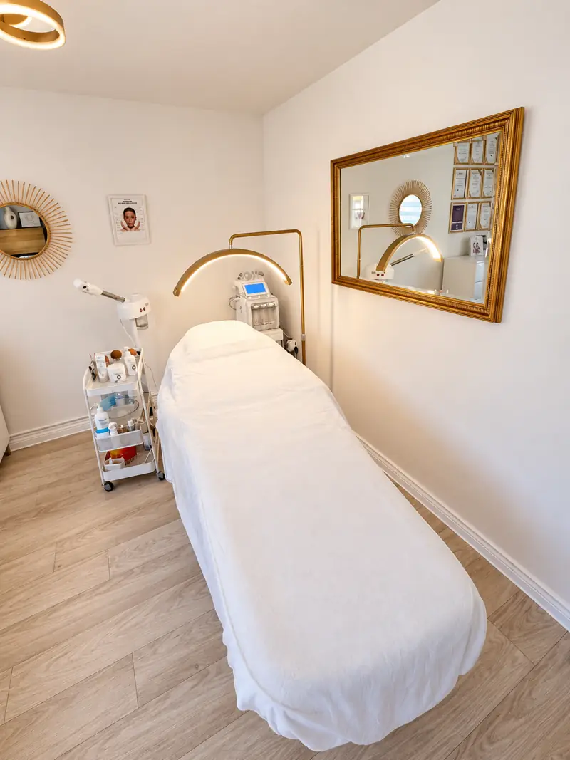 Treatment bed beside a gold-framed mirror at the Costessey studio